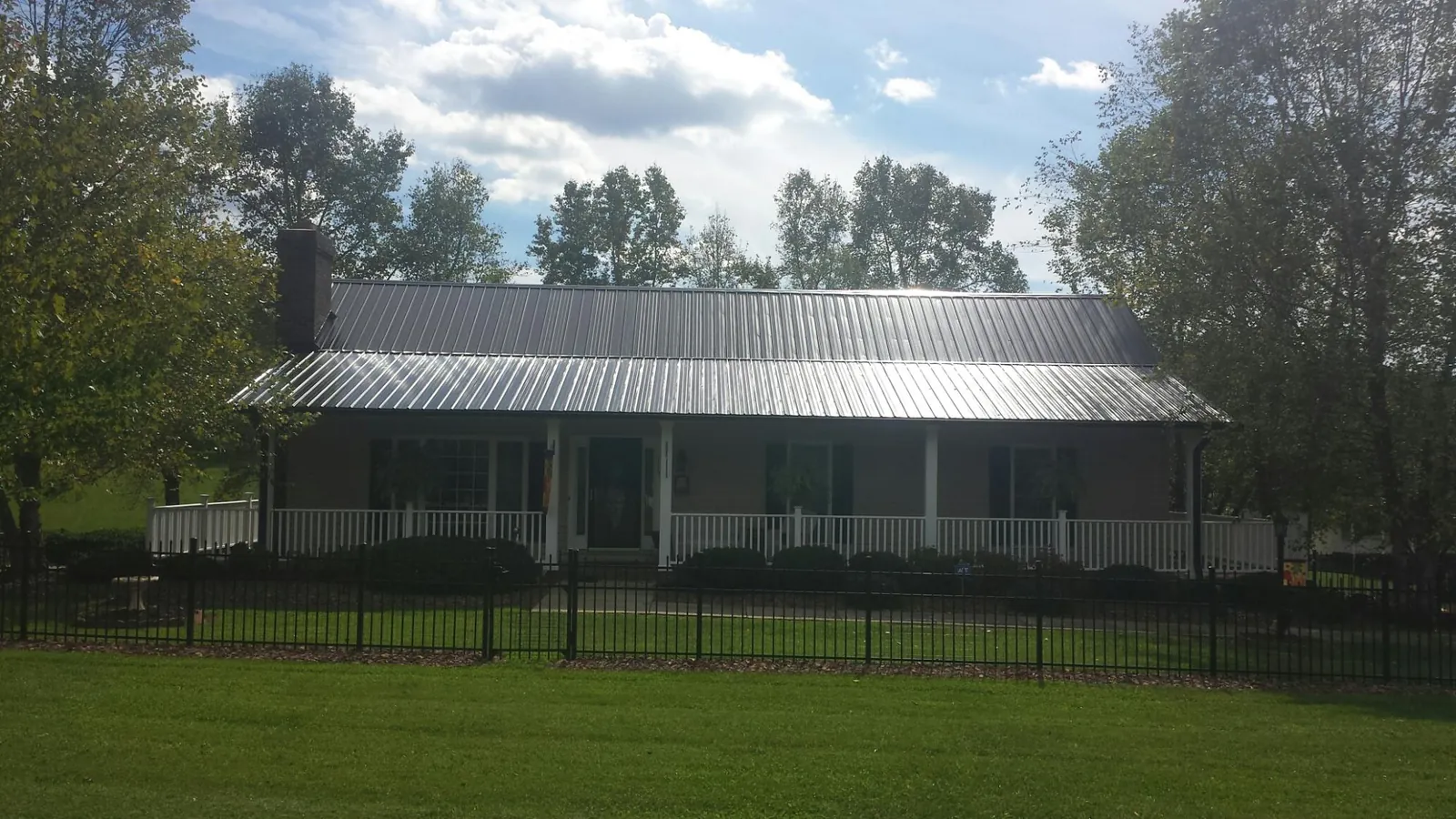 Gray metal roof on a brick ranch with a full width front porch — Gutter Guard Installation work by our crew in Niota